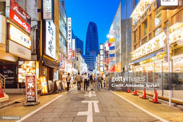 street with shops and restaurants in shinjuku district in tokyo, japan - tokyo japan stock-fotos und bilder