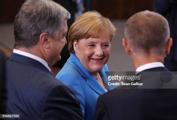 German Chancellor Angela Merkel chats with Ukrainian President Petro Poroshenko and an unidentified man prior to a working session of NATO leaders...
