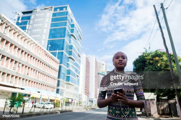 jeune fille africaine écouter de la musique sur les écouteurs de téléphone mobile dans le centre ville - dar photos et images de collection