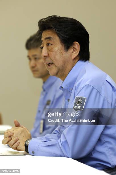 Prime Minister Shinzo Abe speaks to Okayama Prefecture Governor Ryuta Ibaragi during their meeting on July 11, 2018 in Okayama, Japan. The death toll...