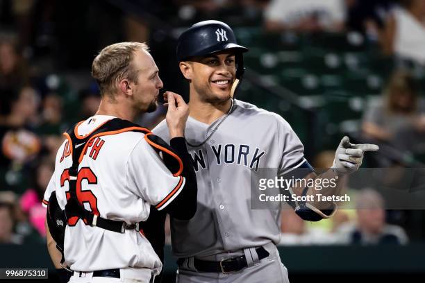 Giancarlo Stanton of the New York Yankees and Caleb Joseph of the Baltimore Orioles talk during the ninth inning at Oriole Park at Camden Yards on...