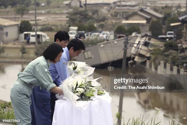Prime Minister Shinzo Abe offer flowers at a hill he can see the submerged area on July 11, 2018 in Kurashiki, Okayama, Japan. The death toll from...