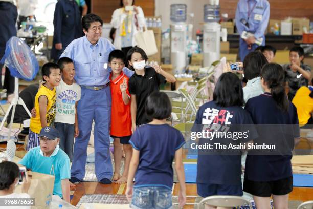 Japanese Prime Minister Shinzo Abe poses for selfie with young evacuees at a gymnasium of the Okada Elementary School where people take shelter after...