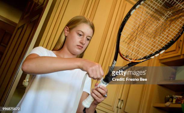 Clovis North high school tennis player Jordan Pickett puts a new overgrip on a tennis racket at her friend and fellow tennis team member Billy...