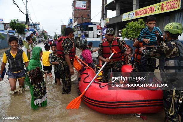 Nepal Army personnel help children and others to cross flood water after the Hanumante River overflowed following monsoon rain in the Thimi area of...