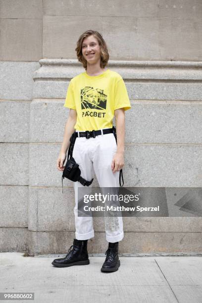 Model is seen on the street during Men's New York Fashion Week wearing yellow shirt with white pants and black utility harness belt on July 11, 2018...