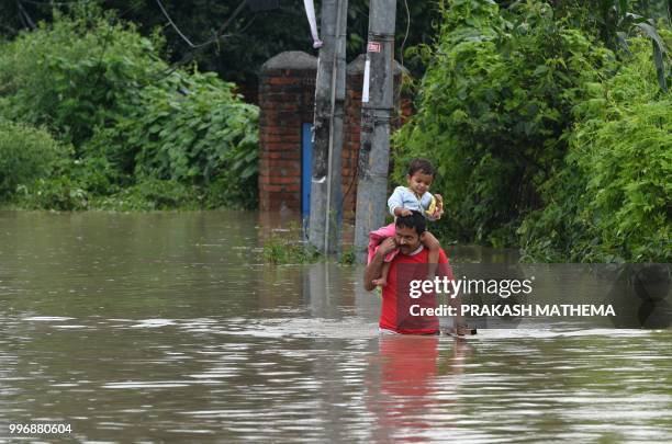 Nepali man carries his child through flood water after the Hanumante River overflowed following monsoon rain in the Thimi area of Bhaktapur on the...