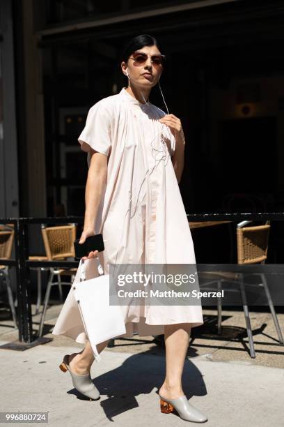 Guest is seen on the street during Men's New York Fashion Week wearing a cream dress with grey heels on July 11, 2018 in New York City.