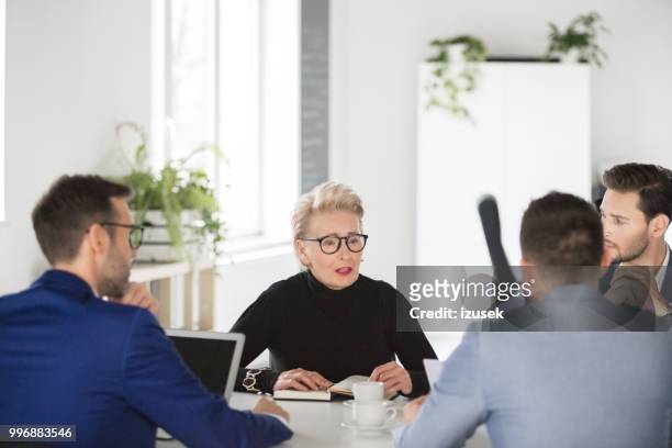 senior zakenvrouw delen ideeën in vergadering - izusek stockfoto's en -beelden