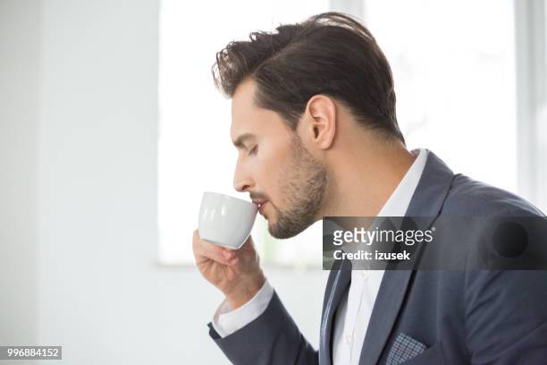 geschäftsmann, trinken kaffee im büro - izusek stock-fotos und bilder