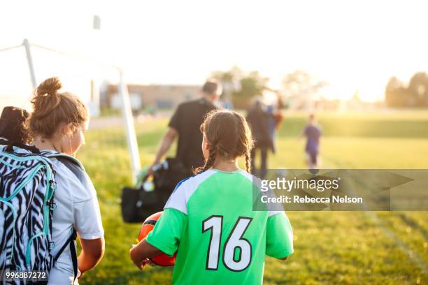 two female soccer players, from oppopsing teams, walking off soccer field - calcio di squadra foto e immagini stock