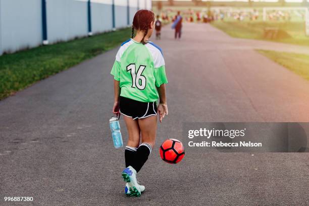 girl dribbling soccer ball to her field to begin play - sports jersey back stock pictures, royalty-free photos & images