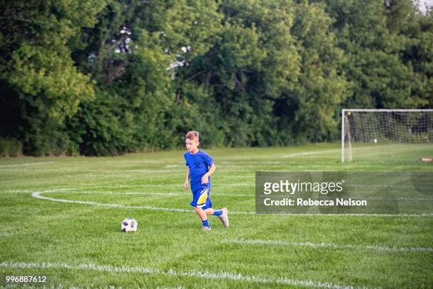 11 year old boy dribbling soccer ball on soccer field - fußballliga stock-fotos und bilder