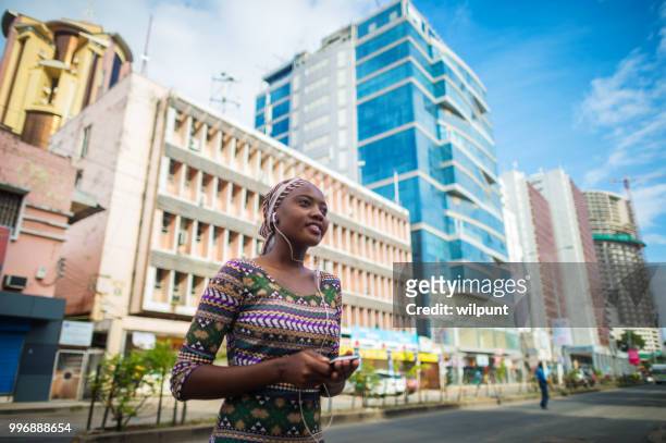 收聽音樂的年輕非洲女孩從手機在市中心的耳機 - dar 個照片及圖片檔