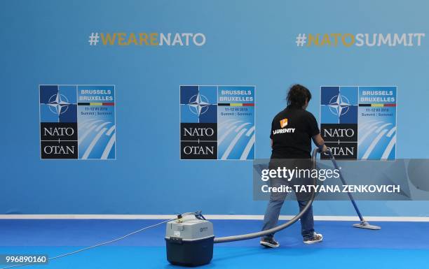 Cleaning staff member vacuums the carpet ahead of the arrival of leaders attending the second day of the North Atlantic Treaty Organization summit in...