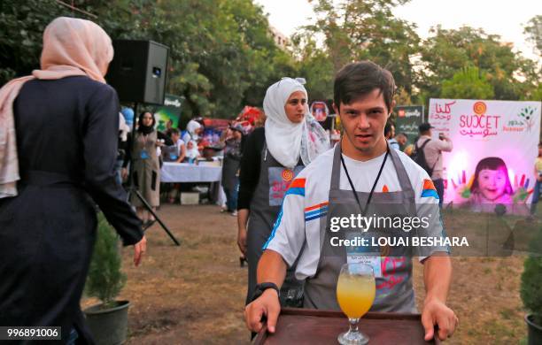 Syrian waiter with Down syndrome works at the Sucet coffee shop during the "Sham gathers us" festival in Damascus on July 11, 2018. - Sixteen boys...