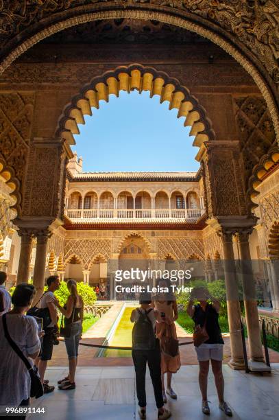 Tourists at the Courtyard Of The Maidens at the Royal Alcazar of Seville, a royal palace built on the grounds of a Abbadid Muslim fortress, Spain.