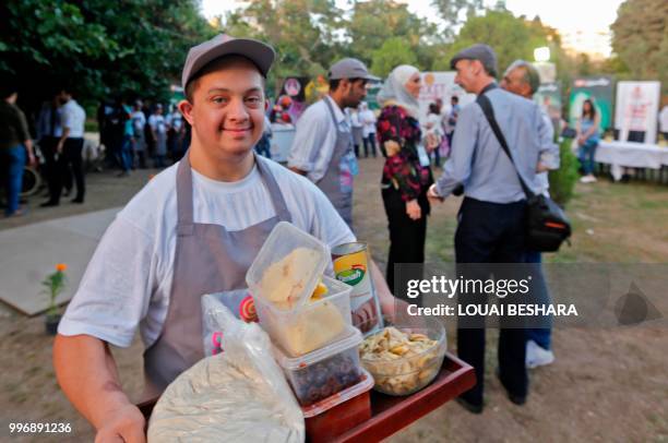 Syrian waiter with Down syndrome works at the Sucet coffee shop during the "Sham gathers us" festival in Damascus on July 11, 2018. - Sixteen boys...