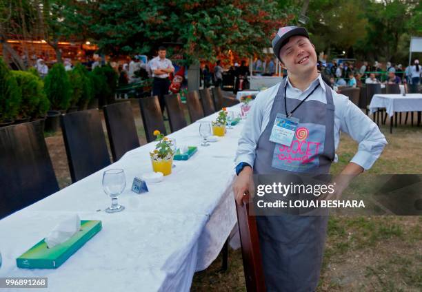 Syrian waiter with Down syndrome Abdel Rahman works at the Sucet coffee shop during the "Sham gathers us" festival in Damascus on July 11, 2018. -...