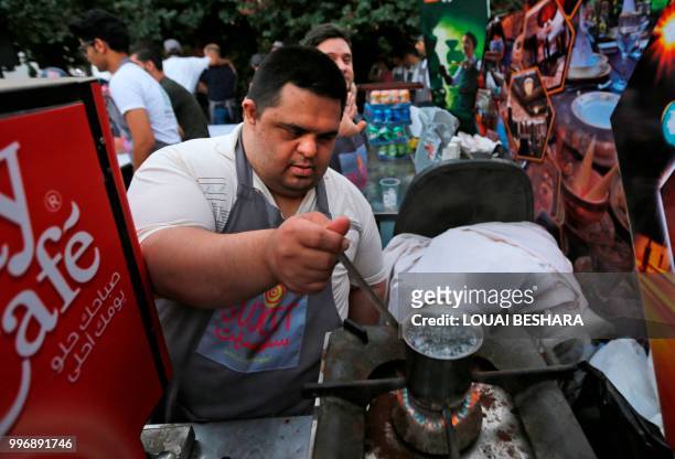 Syrian waiter with Down syndrome Hazem Zahra works at the Sucet coffee shop during the "Sham gathers us" festival in Damascus on July 11, 2018. -...