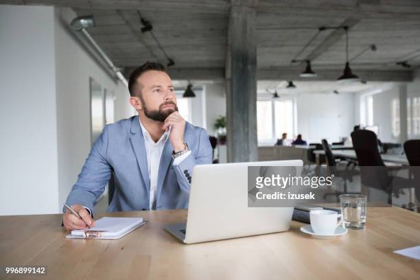 doordachte zakenman aan het werk op kantoor - izusek stockfoto's en -beelden