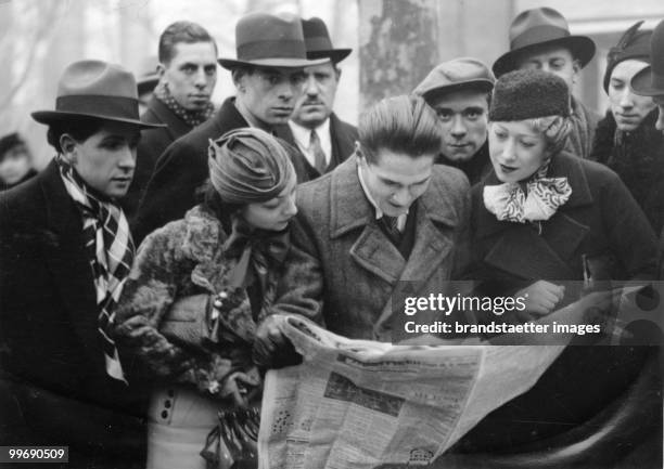 Group of people hustling around a newspaper. Paris. Photographie. Around 1930.