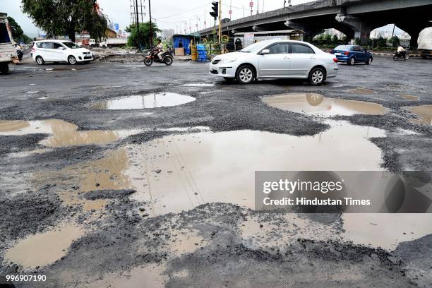 Vehicles make their way on potholes ridden road, on July 11, 2018 in Mumbai, India. Heavy rains made a comeback in Mumbai causing waterlogging in...