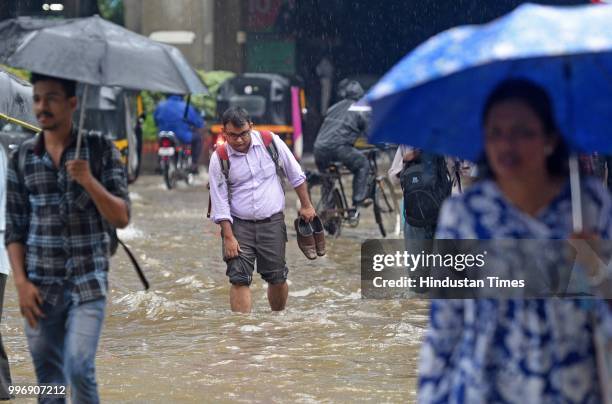 Vehicles and people wade through waterlogged street near WEH metro station at Andhri Kurla Road, on July 11, 2018 in Mumbai, India. Heavy rains made...