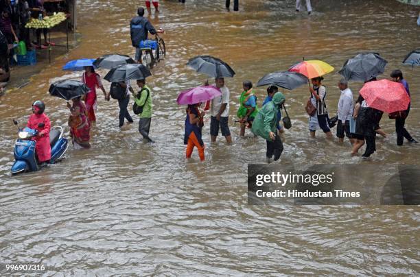 Vehicles and people wade through waterlogged street near WEH metro station at Andhri Kurla Road, on July 11, 2018 in Mumbai, India. Heavy rains made...