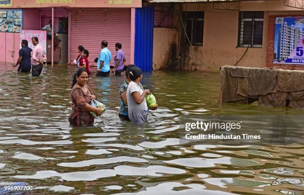 People wades through a water logged street at Nallasopara West Station Road, on July 11, 2018 in Mumbai, India. Heavy rains made a comeback in Mumbai...