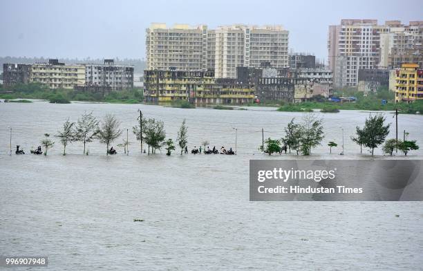 People wades through a water logged street at Evershine Nager Vasai East, on July 11, 2018 in Mumbai, India. Heavy rains made a comeback in Mumbai...