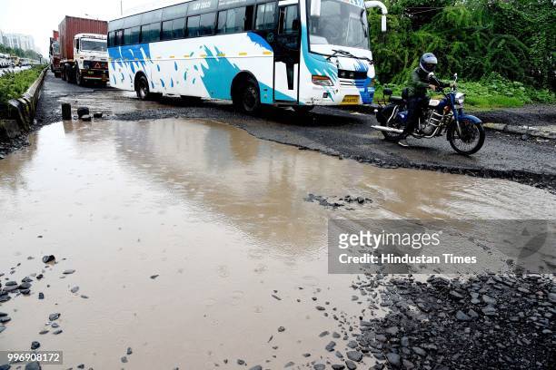 Vehicles make their way on potholes ridden road, on July 11, 2018 in Mumbai, India. Heavy rains made a comeback in Mumbai causing waterlogging in...