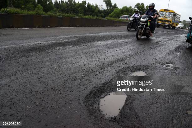 Vehicles make their way on potholes ridden road, on July 11, 2018 in Mumbai, India. Heavy rains made a comeback in Mumbai causing waterlogging in...