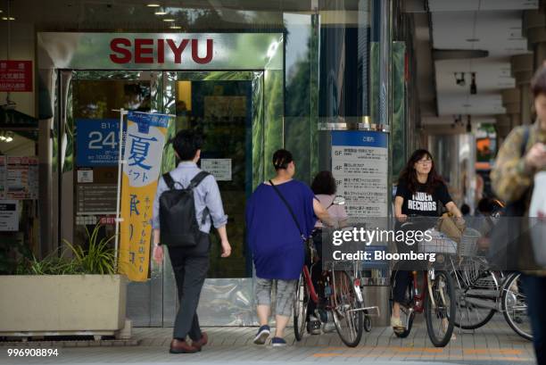 Pedestrians and cyclists pass a Seiyu store, operated by Seiyu GK, in Tokyo, Japan, on Thursday, July 12, 2018. Walmart Inc. Plans to sell its Japan...