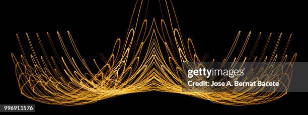 close-up abstract pattern of intertwined colorful light beams of colors yellow and gol colored on a  black background. - gol stock-fotos und bilder