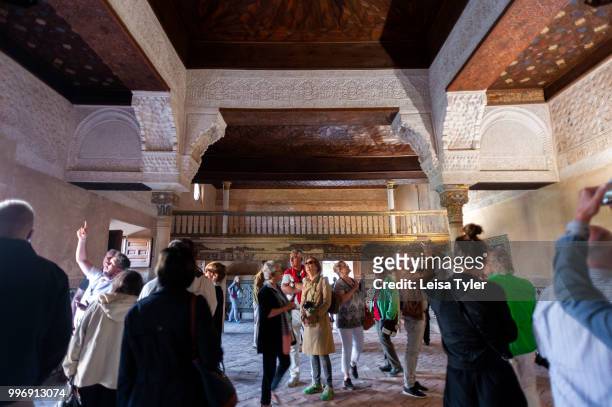Tourists inside the 14th century Mexuar at the Alhambra, a 13th century Moorish palace complex in Granada, Spain. Built on Roman ruins, the Alhambra...
