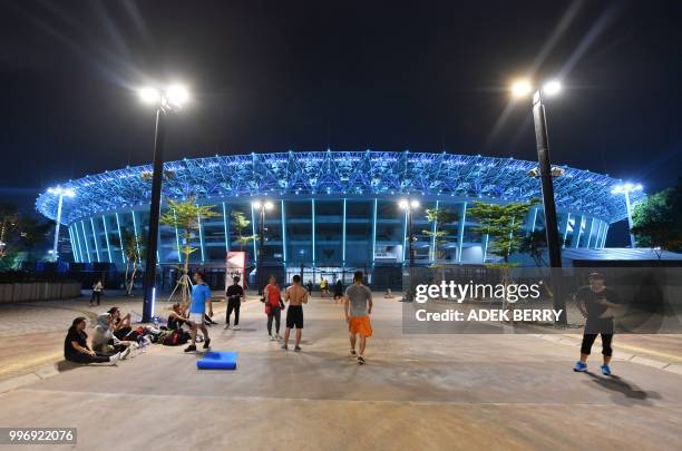 This picture taken on July 11, 2018 shows people outside Gelora Bung Karno stadium where opening and closing ceremonies for the 2018 Asian Games will...