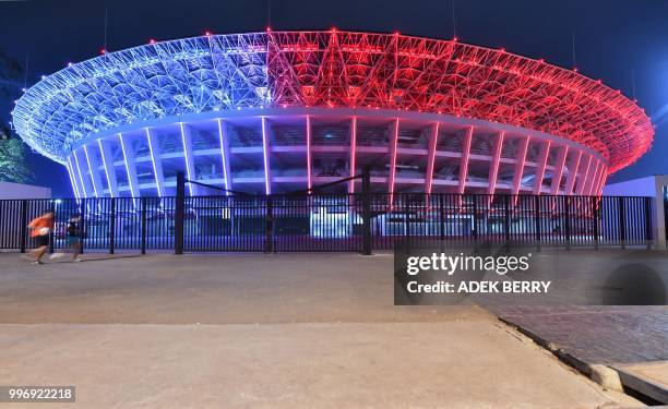 This picture taken on July 11, 2018 shows people jogging outside Gelora Bung Karno stadium where opening and closing ceremonies for the 2018 Asian...