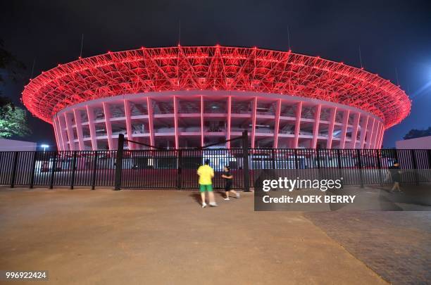 This picture taken on July 11, 2018 shows people outside Gelora Bung Karno stadium where opening and closing ceremonies for the 2018 Asian Games will...