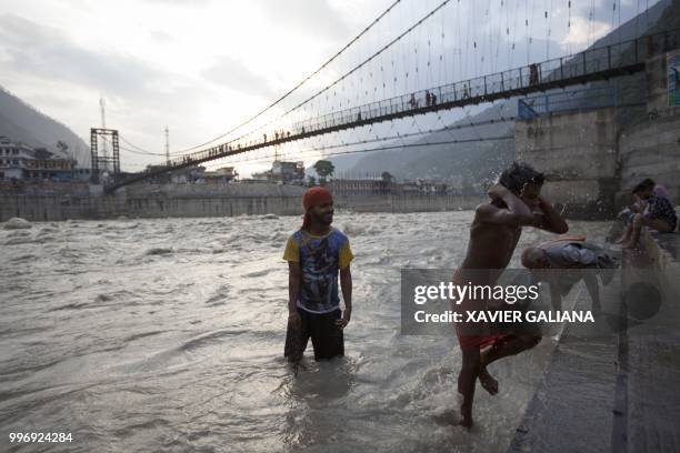 In this photograph taken on July 11 Indian Hindu devotees bathe in the Bhagiathi River in Uttarkashi, in the northern state of Uttarakhand.