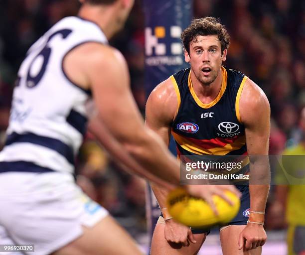 Kyle Hartigan of the Crows looks on as Tom Hawkins of the Cats kicks the ball during the round 17 AFL match between the Adelaide Crows and the...