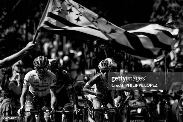 Spectator waves the flag of Brittany as Latvia's Toms Skujins , France's Lilian Calmejane and France's Nicolas Edet ride during a three-men breakaway...