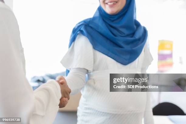 confident businesswoman greeting colleague - pregnant muslim stock pictures, royalty-free photos & images