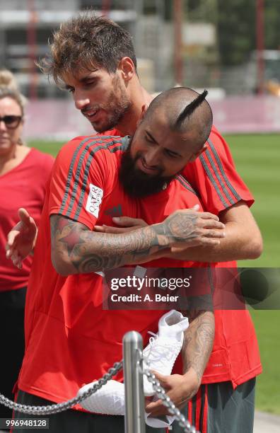 Arturo Vidal of FC Bayern Muenchen is hugged by his teammate Javi Martinez after a training session at the club's Saebener Strasse training ground on...