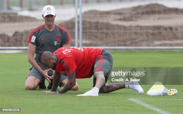 Arturo Vidal of FC Bayern Muenchen stretches next to fitness coach Thomas Wilhelmi during training session at the club's Saebener Strasse training...