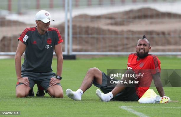 Arturo Vidal of FC Bayern Muenchen rests next to fitness coach Thomas Wilhelmi during a training session at the club's Saebener Strasse training...