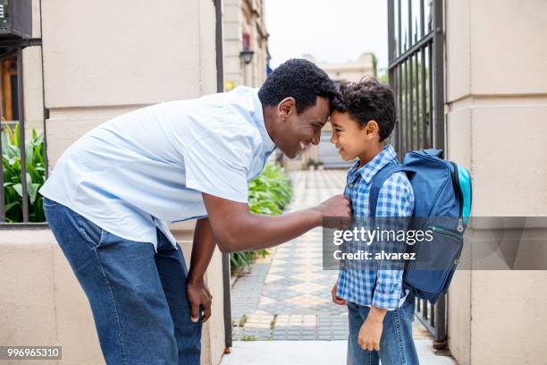 padre sonriente dejando a hijo con mochila a la escuela - first day of school fotografías e imágenes de stock