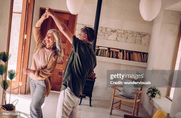 happy mature couple dancing and celebrating together at home - the twist stock pictures, royalty-free photos & images