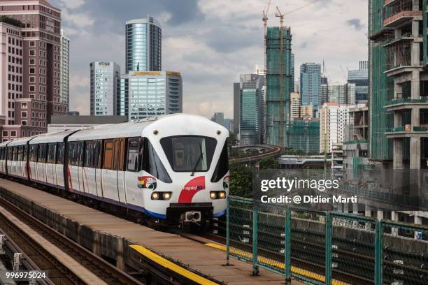 elevated train reaching a platform in kuala lumpur with tower of the downtown district in the background in malaysia - didier marti stock pictures, royalty-free photos & images
