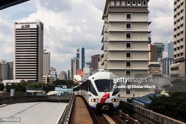 elevated train reaching a platform in kuala lumpur with tower of the downtown district in the background in malaysia - didier marti stock pictures, royalty-free photos & images